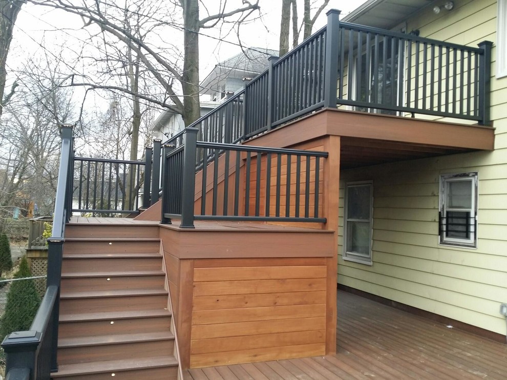 Example of a huge mountain style backyard balcony deck design in New York with a roof extension