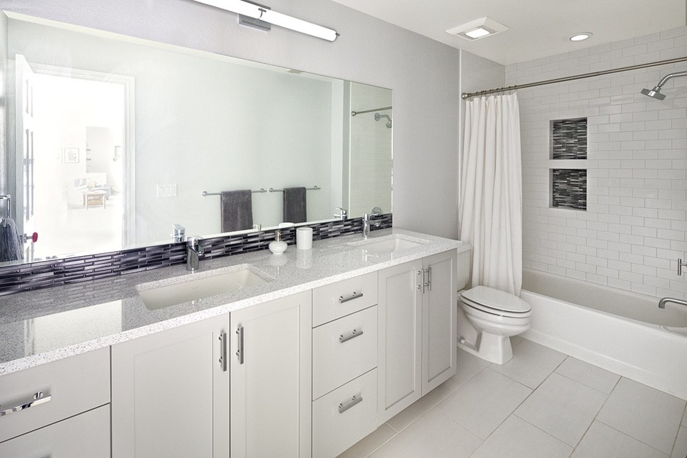 This is an example of a small transitional kids bathroom in Denver with recessed-panel cabinets, grey cabinets, an alcove tub, an alcove shower, a two-piece toilet, gray tile, grey walls, porcelain floors, an undermount sink, engineered quartz benchtops, white floor, a shower curtain and multi-coloured benchtops.