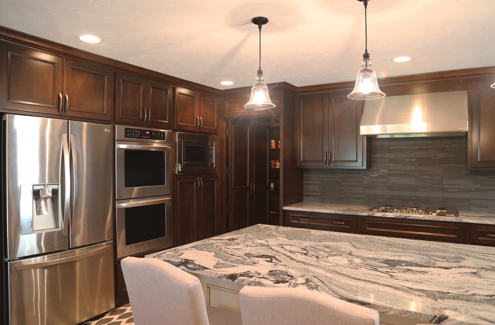 Eat-in kitchen - mid-sized transitional l-shaped porcelain tile eat-in kitchen idea with an undermount sink, raised-panel cabinets, dark wood cabinets, granite countertops, gray backsplash, porcelain backsplash, stainless steel appliances and an island