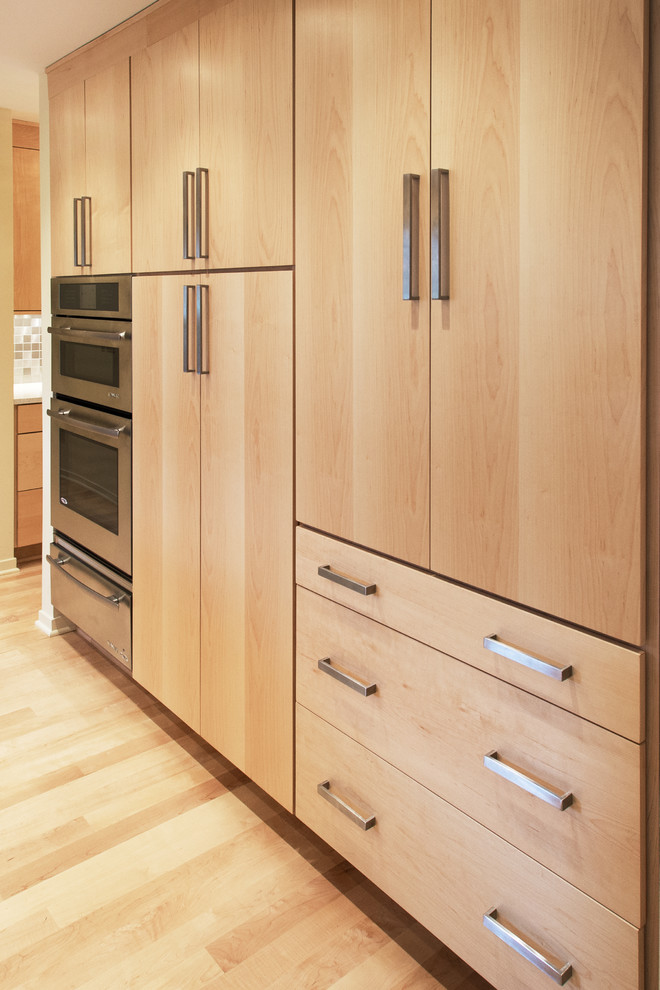 Large transitional u-shaped light wood floor eat-in kitchen photo with an undermount sink, flat-panel cabinets, light wood cabinets, quartzite countertops, metallic backsplash, metal backsplash, stainless steel appliances and an island