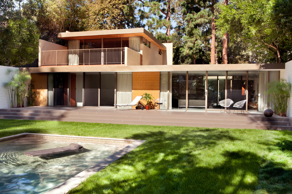 This is an example of a midcentury exterior in Los Angeles with wood siding and a flat roof.