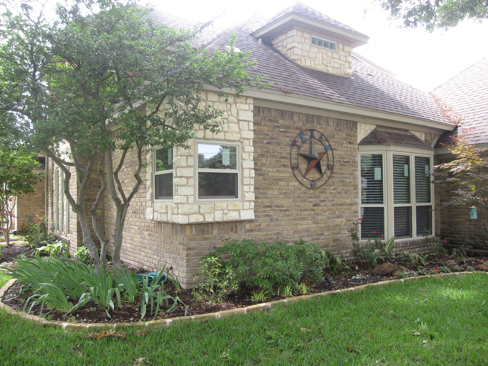 This is an example of a large traditional two-storey beige exterior in Dallas with stone veneer and a gable roof.