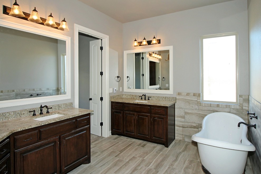 Claw-foot bathtub - large transitional master multicolored tile and porcelain tile porcelain tile claw-foot bathtub idea with raised-panel cabinets, dark wood cabinets, a two-piece toilet, white walls, an undermount sink and granite countertops