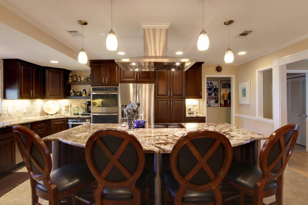Eat-in kitchen - large transitional l-shaped porcelain tile eat-in kitchen idea in Miami with an undermount sink, raised-panel cabinets, dark wood cabinets, granite countertops, beige backsplash, stone tile backsplash, stainless steel appliances and an island