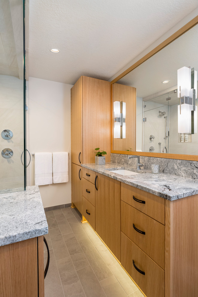 Inspiration for a medium sized modern ensuite bathroom in Minneapolis with flat-panel cabinets, light wood cabinets, a two-piece toilet, white tiles, porcelain tiles, white walls, porcelain flooring, a submerged sink, granite worktops, grey floors, a hinged door, grey worktops, a shower bench, a single sink and a built in vanity unit.