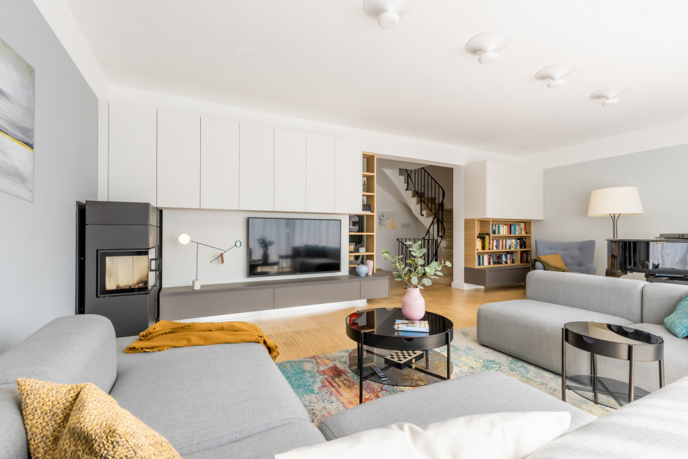 Large scandinavian open concept family room in Dusseldorf with a music area, grey walls, bamboo floors, a hanging fireplace, a metal fireplace surround, a wall-mounted tv, brown floor, wallpaper and wallpaper.