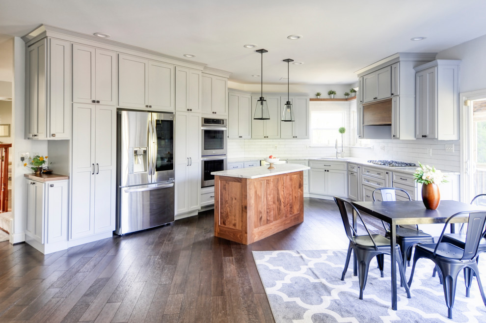 Mid-sized country u-shaped eat-in kitchen in DC Metro with an undermount sink, recessed-panel cabinets, grey cabinets, quartz benchtops, subway tile splashback, stainless steel appliances, dark hardwood floors, with island, brown floor and white benchtop.