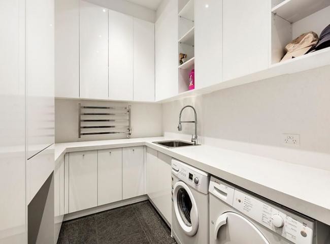 Mid-sized modern u-shaped dedicated laundry room in Melbourne with a drop-in sink, flat-panel cabinets, white cabinets, quartz benchtops, white walls, porcelain floors and a side-by-side washer and dryer.