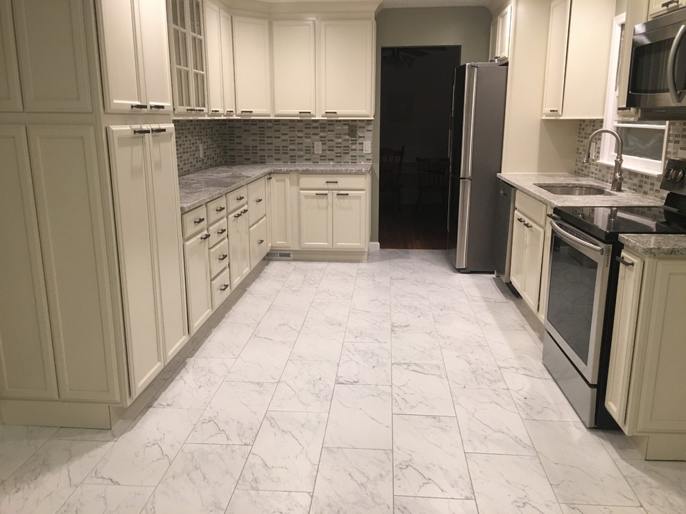 Photo of a mid-sized traditional u-shaped separate kitchen in DC Metro with an undermount sink, recessed-panel cabinets, white cabinets, granite benchtops, grey splashback, glass tile splashback, stainless steel appliances, ceramic floors, white floor and grey benchtop.