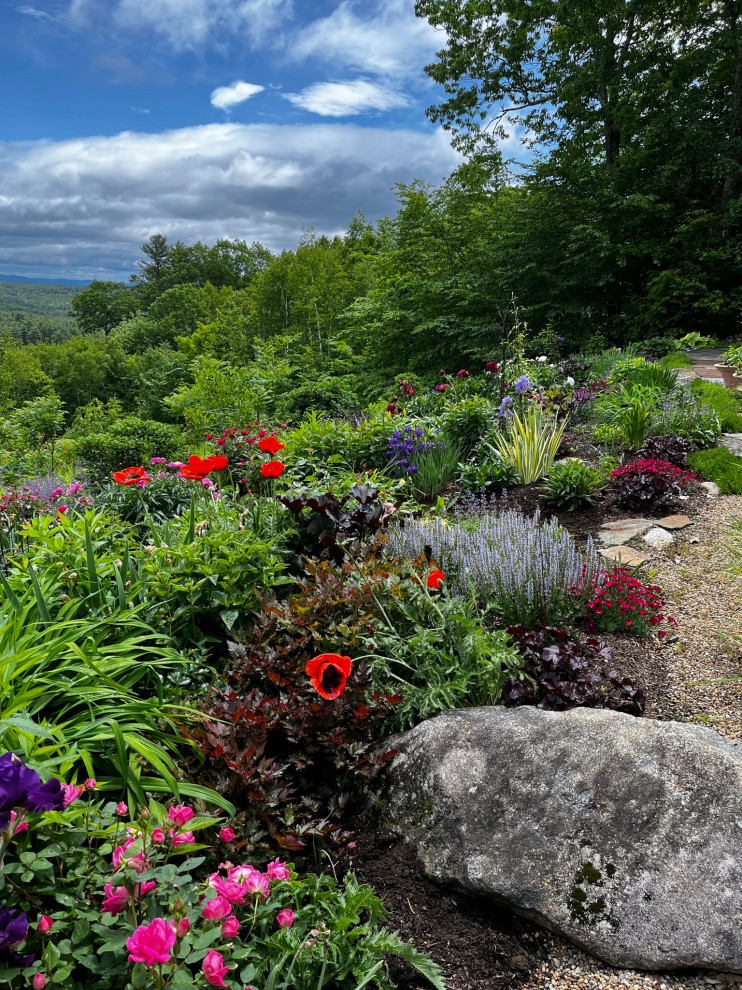 This is an example of a large transitional full sun hillside stone landscaping for summer.