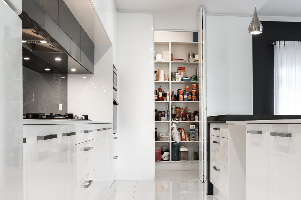 Photo of a mid-sized contemporary l-shaped kitchen pantry in Adelaide with a double-bowl sink, flat-panel cabinets, white cabinets, quartz benchtops, black splashback, glass sheet splashback, stainless steel appliances, ceramic floors and with island.