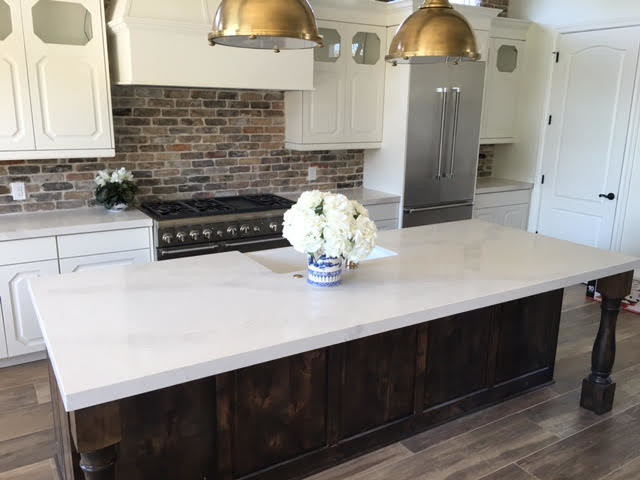 Kitchen - mid-sized transitional single-wall kitchen idea in Austin with a farmhouse sink, raised-panel cabinets, white cabinets, stainless steel appliances and an island