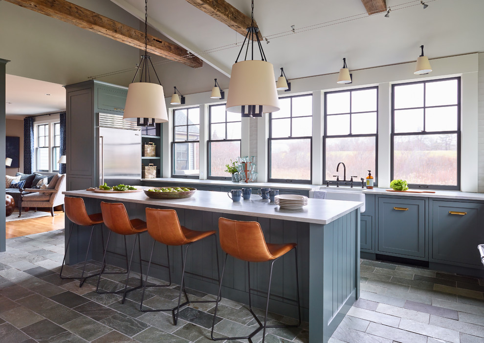Mid-sized transitional l-shaped separate kitchen in Boston with a farmhouse sink, shaker cabinets, blue cabinets, quartzite benchtops, white splashback, subway tile splashback, stainless steel appliances, slate floors, with island, grey floor and white benchtop.
