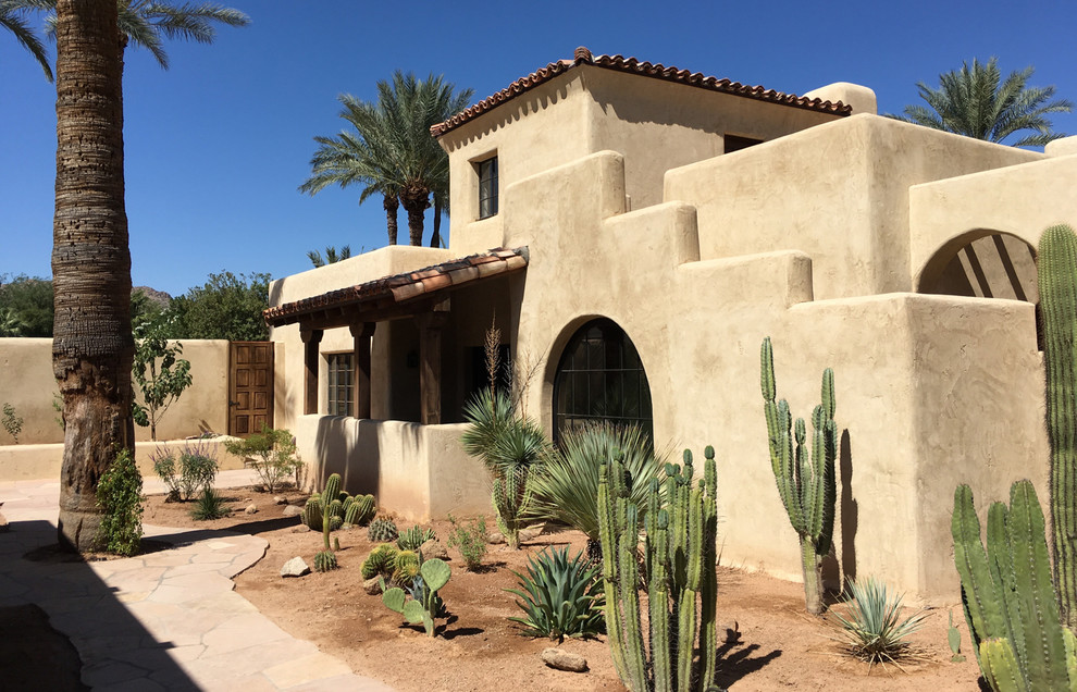 Expansive two-storey adobe beige house exterior in Phoenix with a hip roof and a tile roof.