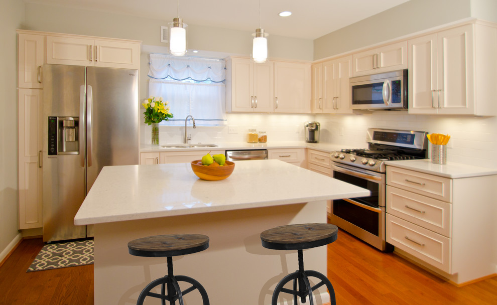 Inspiration for a mid-sized transitional l-shaped separate kitchen in DC Metro with a double-bowl sink, recessed-panel cabinets, white cabinets, quartz benchtops, white splashback, cement tile splashback, stainless steel appliances, medium hardwood floors and with island.