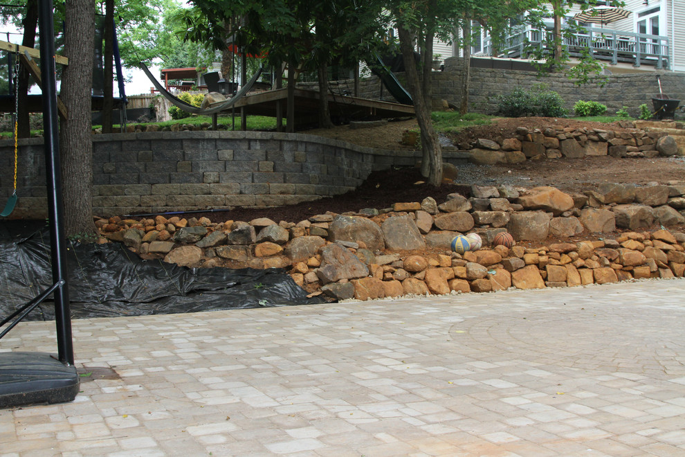 Large arts and crafts sloped outdoor sport court in Other with a retaining wall and natural stone pavers.