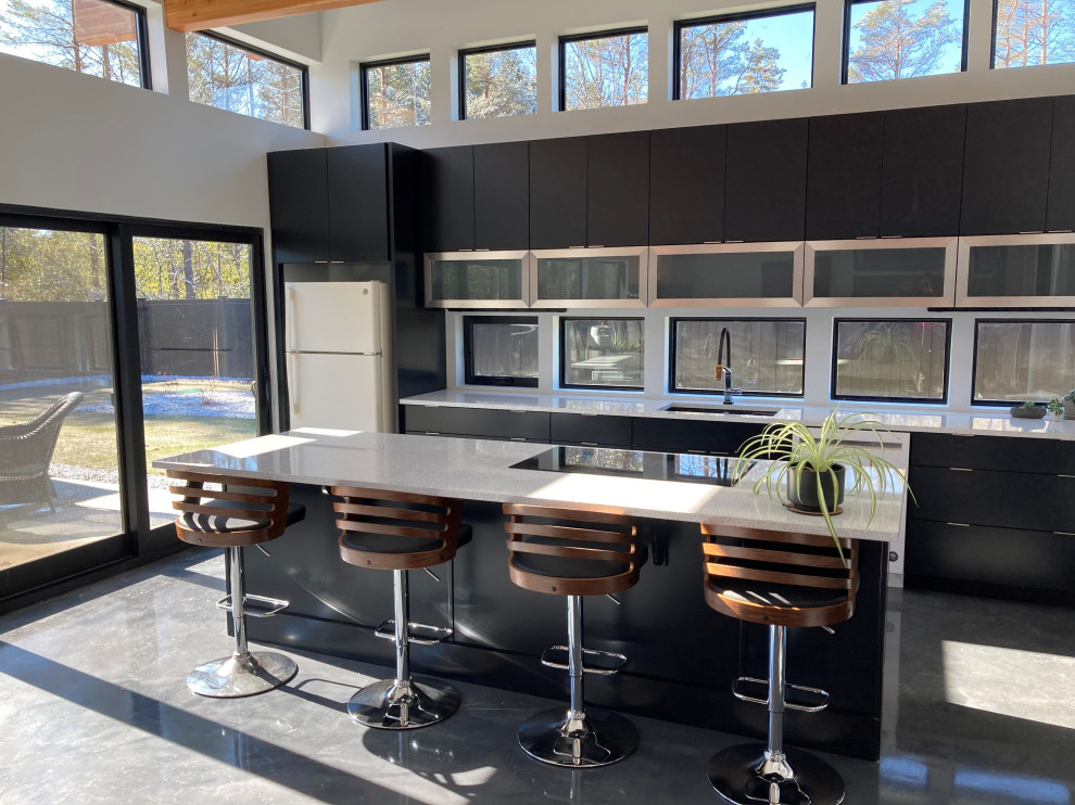 This is an example of a mid-sized modern galley eat-in kitchen in New York with an undermount sink, flat-panel cabinets, black cabinets, quartz benchtops, window splashback, white appliances, concrete floors, with island, grey floor, white benchtop and exposed beam.