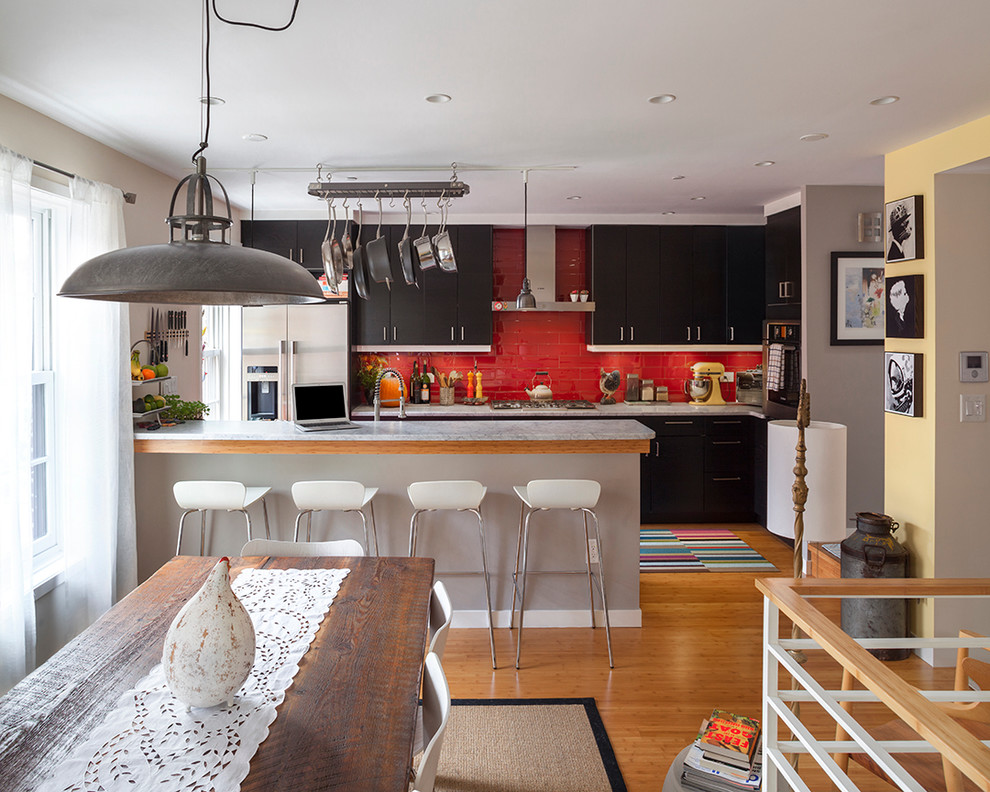 Contemporary galley eat-in kitchen in New York with flat-panel cabinets, black cabinets, red splashback and subway tile splashback.