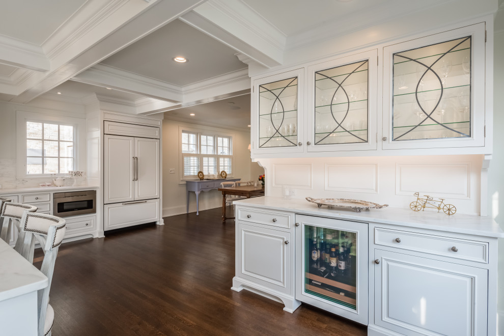 Example of a large transitional l-shaped medium tone wood floor and brown floor open concept kitchen design in Milwaukee with an undermount sink, recessed-panel cabinets, white cabinets, marble countertops, white backsplash, marble backsplash, stainless steel appliances, an island and white countertops