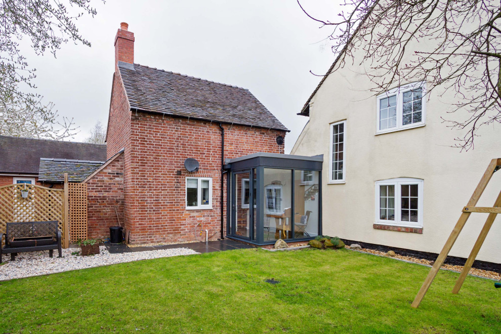 Photo of a small and red rustic two floor brick detached house in West Midlands with a pitched roof and a tiled roof.