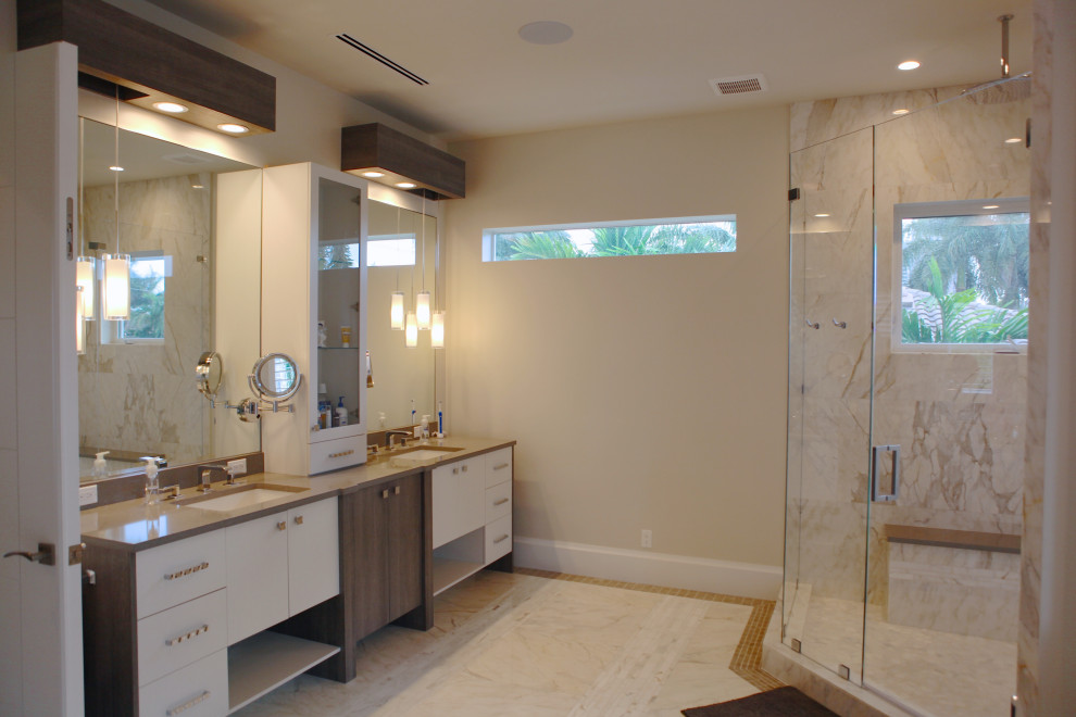 This is an example of a large tropical master bathroom in Miami with beige cabinets, a corner shower, beige tile, marble, granite benchtops, beige benchtops, a double vanity and a built-in vanity.
