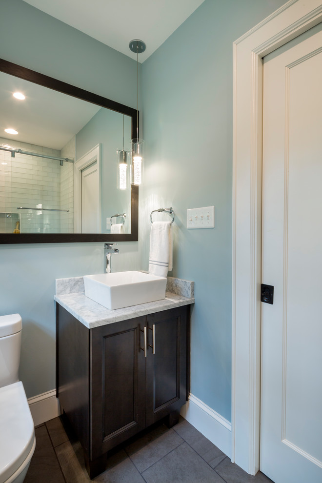 Small transitional kids bathroom in Charlotte with flat-panel cabinets, dark wood cabinets, an alcove tub, a shower/bathtub combo, a one-piece toilet, white tile, glass tile, blue walls, ceramic floors, a vessel sink, marble benchtops, grey floor and a sliding shower screen.