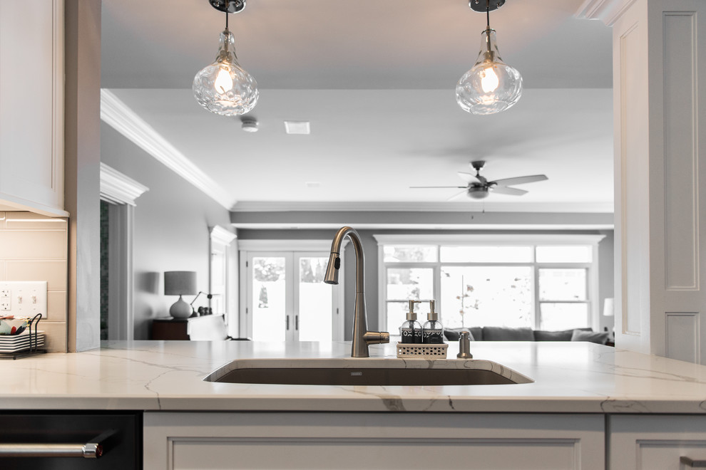 Example of a mid-sized transitional l-shaped medium tone wood floor and brown floor eat-in kitchen design in Chicago with an undermount sink, recessed-panel cabinets, white cabinets, quartzite countertops, gray backsplash, subway tile backsplash, black appliances, no island and multicolored countertops