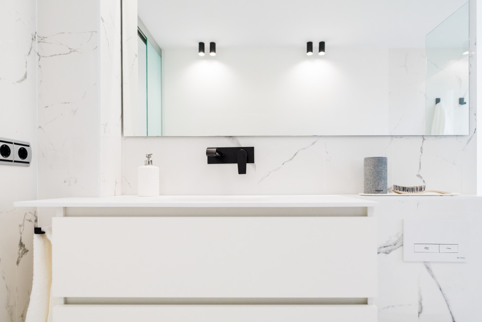 Modelo de cuarto de baño principal minimalista grande con armarios tipo mueble, puertas de armario blancas, ducha a ras de suelo, baldosas y/o azulejos blancas y negros, baldosas y/o azulejos de mármol, paredes blancas, suelo de mármol, lavabo bajoencimera, encimera de acrílico, suelo gris, ducha con puerta corredera y encimeras blancas