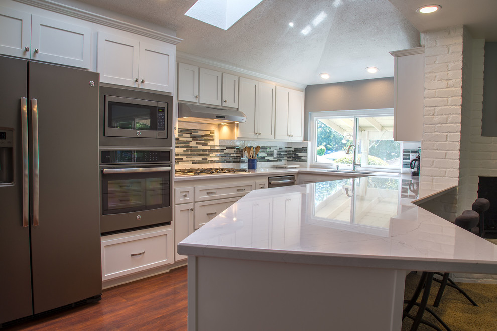 Inspiration for a mid-sized transitional u-shaped dark wood floor eat-in kitchen remodel in Sacramento with an undermount sink, shaker cabinets, white cabinets, quartz countertops, multicolored backsplash, glass tile backsplash, colored appliances and a peninsula