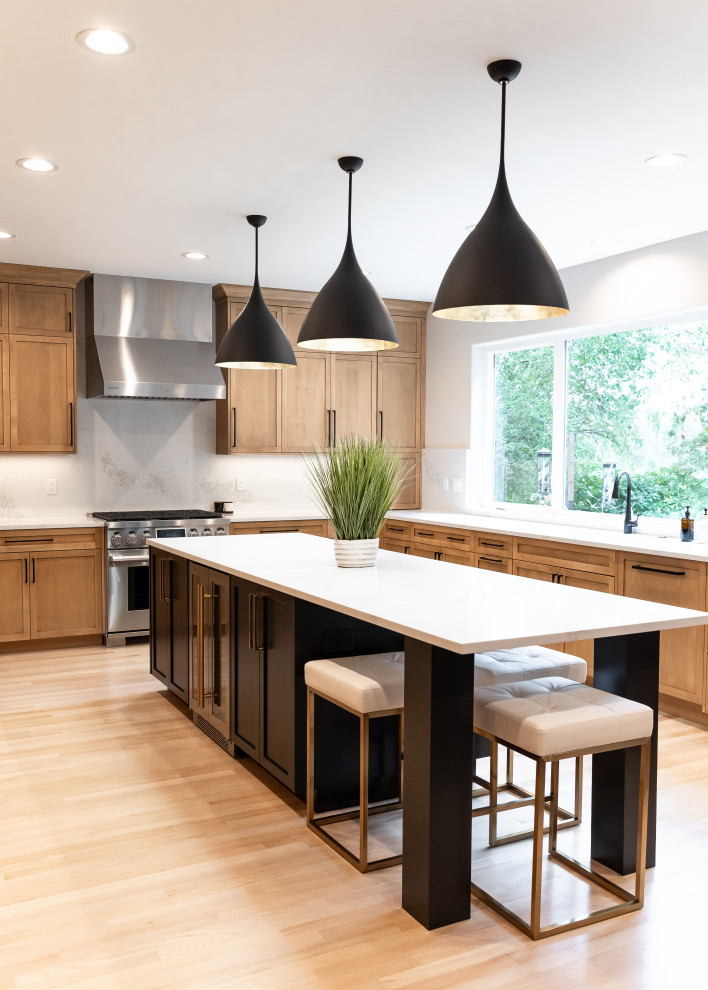 This is an example of a large scandinavian eat-in kitchen in Portland with shaker cabinets, light wood cabinets, quartzite benchtops, white splashback, stainless steel appliances, light hardwood floors, with island, beige floor and white benchtop.
