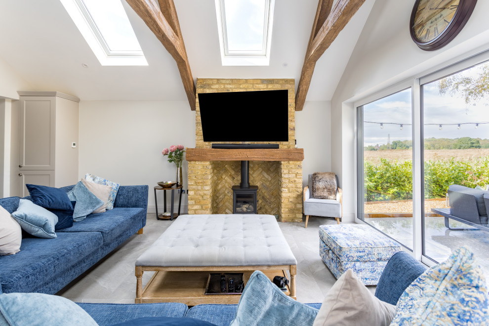 Inspiration for a medium sized rural open plan living room in Surrey with white walls, porcelain flooring, a wood burning stove, a brick fireplace surround, a wall mounted tv, grey floors and a vaulted ceiling.