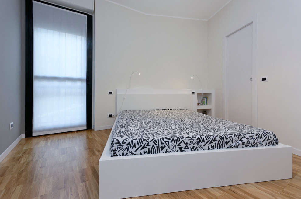 This is an example of a small contemporary master bedroom in Milan with white walls and light hardwood floors.