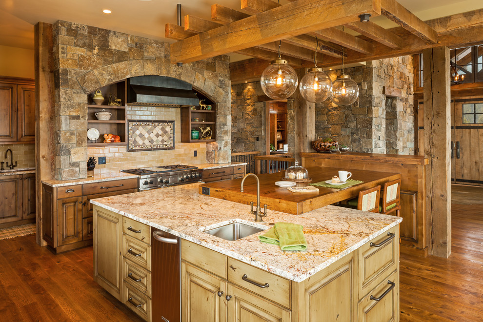 Example of a mountain style medium tone wood floor kitchen design with an undermount sink, raised-panel cabinets, medium tone wood cabinets, beige backsplash, subway tile backsplash and stainless steel appliances