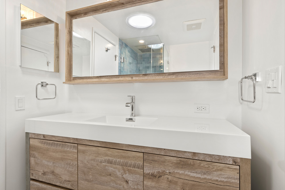 Photo of a medium sized modern ensuite bathroom in Los Angeles with raised-panel cabinets, black cabinets, a corner shower, a one-piece toilet, black tiles, wood-effect tiles, white walls, marble flooring, a built-in sink, marble worktops, white floors, a hinged door, white worktops, a single sink, a freestanding vanity unit and a drop ceiling.