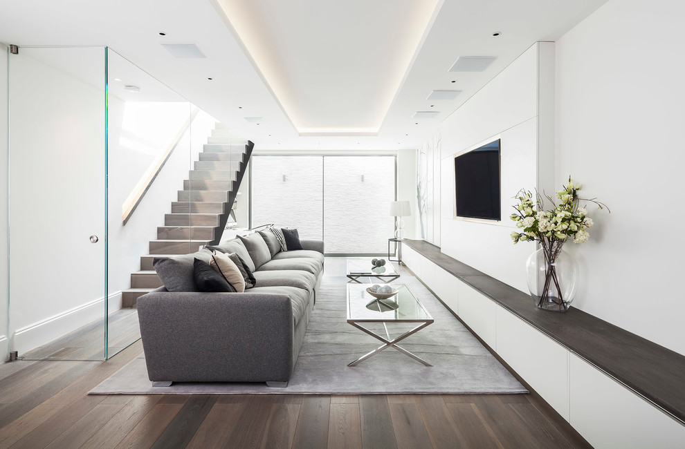 This is an example of a large contemporary formal open concept living room in London with white walls, medium hardwood floors, no fireplace and a wall-mounted tv.