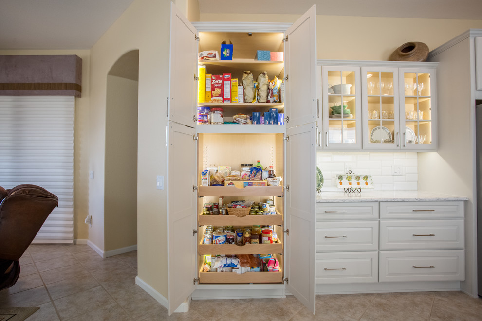 Inspiration for a mid-sized transitional single-wall ceramic tile and beige floor eat-in kitchen remodel with an undermount sink, raised-panel cabinets, white cabinets, quartz countertops, white backsplash, porcelain backsplash, stainless steel appliances and an island