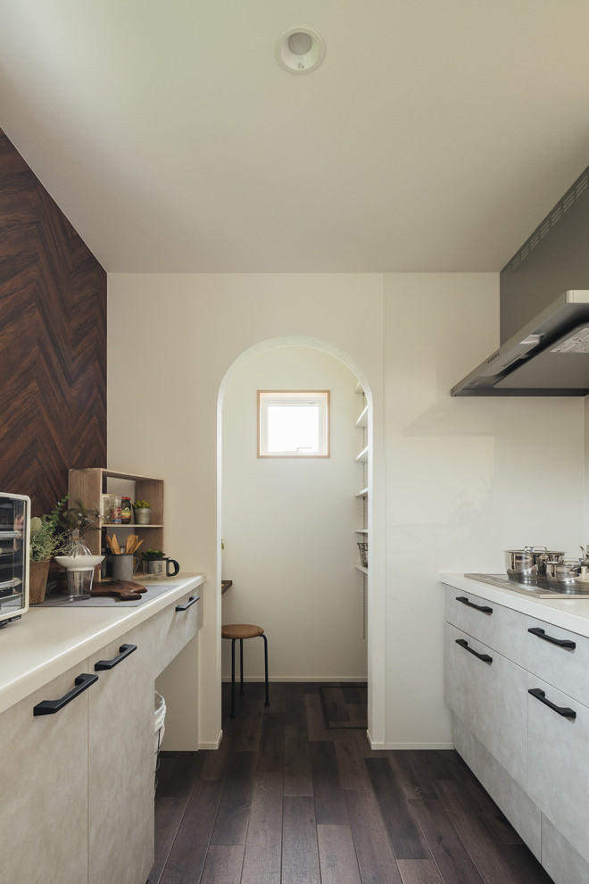Стильный дизайн: прямая кухня-гостиная среднего размера с плоскими фасадами, серыми фасадами, серым фартуком, техникой из нержавеющей стали, полуостровом, коричневым полом и потолком с обоями - последний тренд