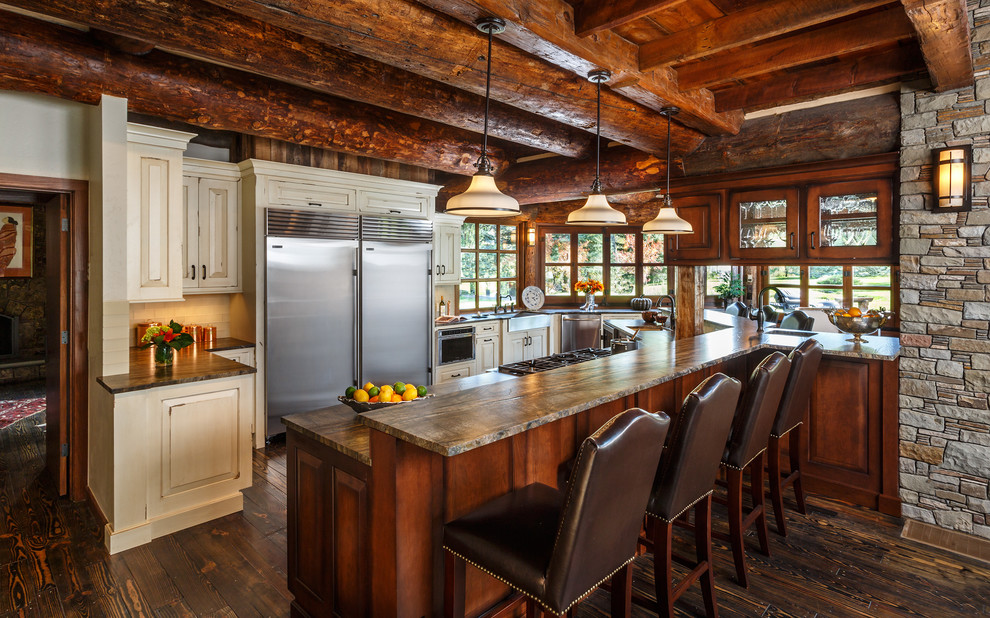 Example of a mountain style u-shaped dark wood floor kitchen design in Albuquerque with raised-panel cabinets, beige cabinets, a peninsula, an undermount sink and stainless steel appliances