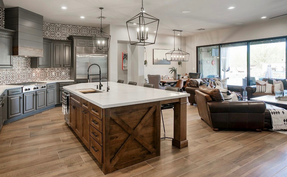 Open concept kitchen - mid-sized transitional l-shaped porcelain tile and brown floor open concept kitchen idea in Phoenix with a single-bowl sink, recessed-panel cabinets, gray cabinets, quartz countertops, multicolored backsplash, porcelain backsplash, stainless steel appliances, an island and white countertops