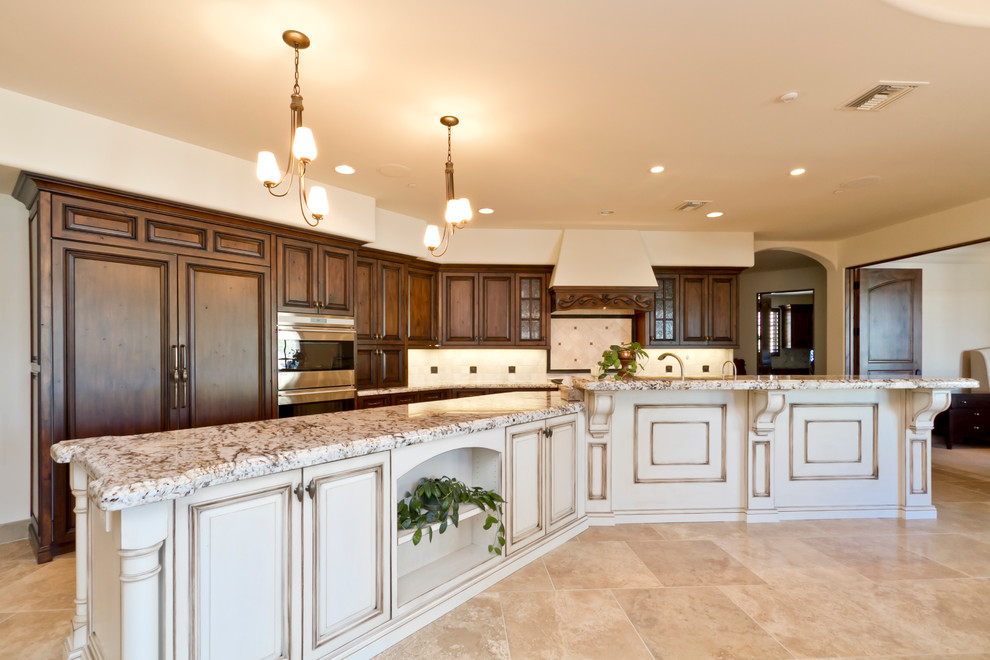 Inspiration for a large mediterranean galley eat-in kitchen in Phoenix with an undermount sink, distressed cabinets, granite benchtops, beige splashback, stone tile splashback, stainless steel appliances and with island.