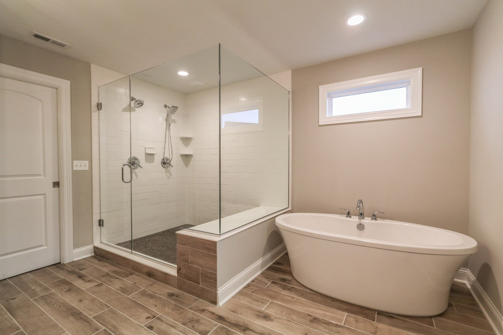 This is an example of a mid-sized contemporary master bathroom in Chicago with a freestanding tub, a corner shower, white tile, subway tile, beige walls, vinyl floors, brown floor and a hinged shower door.