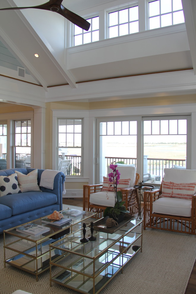 This is an example of a large beach style formal open concept living room in Philadelphia with beige walls, medium hardwood floors, a standard fireplace, a brick fireplace surround, a wall-mounted tv and brown floor.