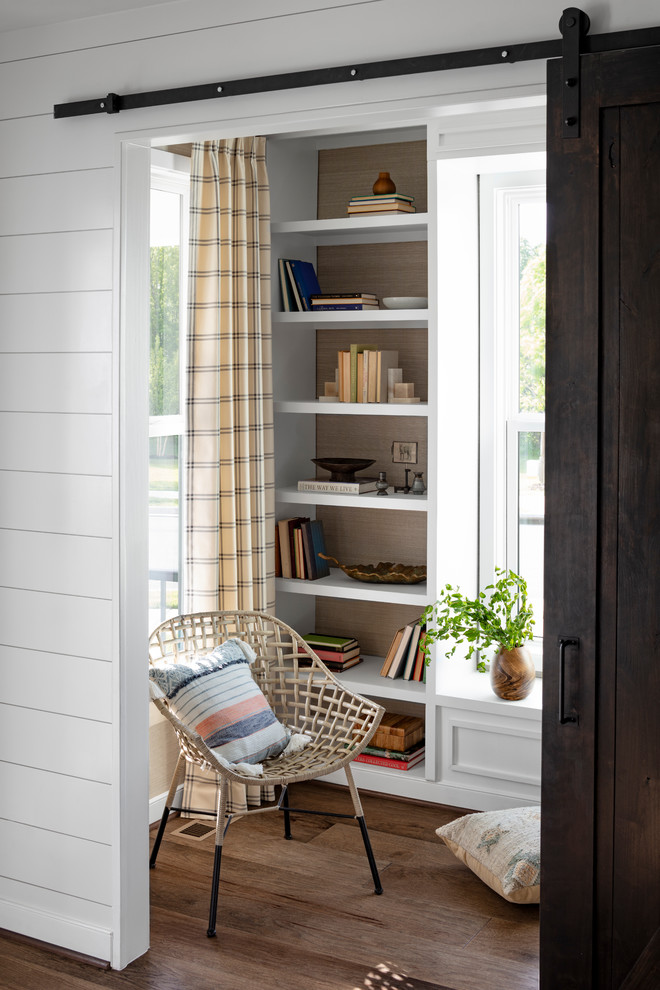 Design ideas for a mid-sized country home office in DC Metro with a library, dark hardwood floors, a freestanding desk, brown floor and white walls.
