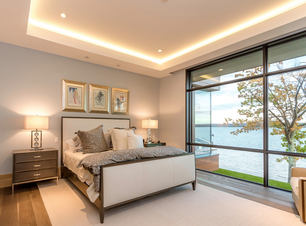 На фото: большая хозяйская спальня в стиле модернизм с светлым паркетным полом, коричневым полом, многоуровневым потолком и серыми стенами с