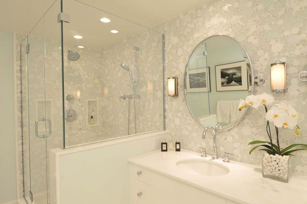 This is an example of a mid-sized contemporary master bathroom in Boston with an undermount sink, furniture-like cabinets, white cabinets, solid surface benchtops, an alcove shower, a one-piece toilet, green tile, glass tile, green walls, marble floors, a hinged shower door, white floor and white benchtops.