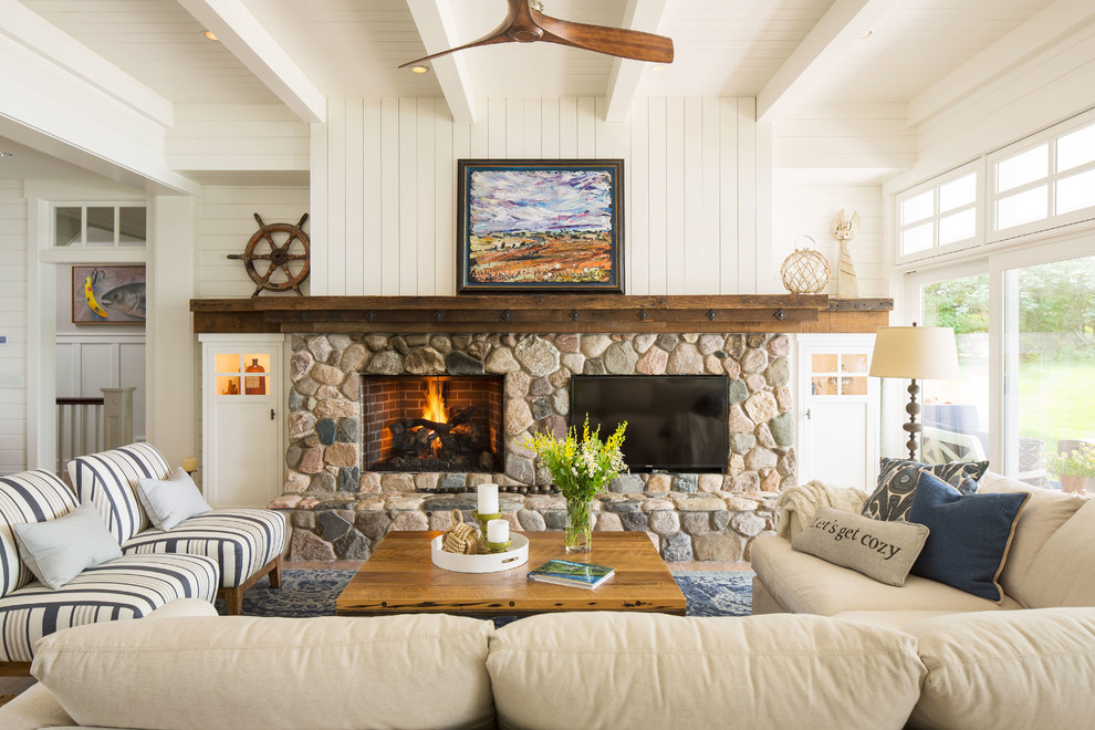 Inspiration for a beach style family room in Minneapolis with white walls, a standard fireplace, a stone fireplace surround and a wall-mounted tv.