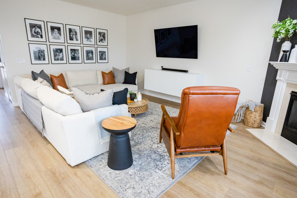Cette image montre un salon minimaliste de taille moyenne et ouvert avec une salle de réception, un mur blanc, un sol en vinyl, une cheminée standard, un manteau de cheminée en plâtre, un téléviseur fixé au mur et un sol marron.