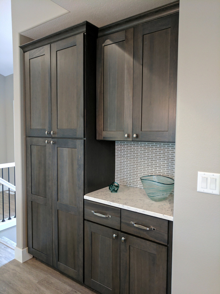 Open concept kitchen - mid-sized rustic galley laminate floor and beige floor open concept kitchen idea in Cedar Rapids with a double-bowl sink, shaker cabinets, dark wood cabinets, quartz countertops, gray backsplash, matchstick tile backsplash, stainless steel appliances and an island