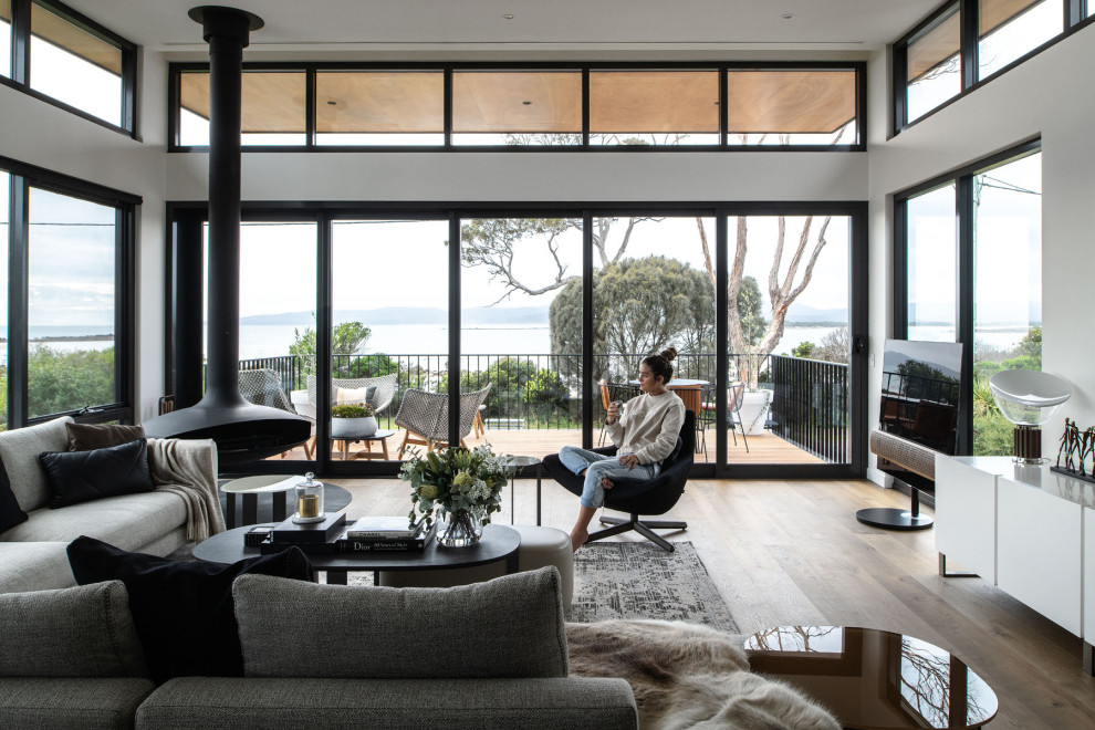 Foto di un soggiorno design aperto con pareti bianche, pavimento in legno massello medio, camino sospeso, TV autoportante e pavimento marrone