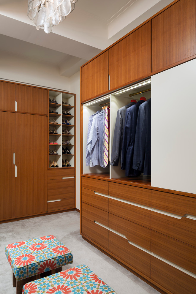 This is an example of a contemporary gender-neutral dressing room in New York with flat-panel cabinets, medium wood cabinets and carpet.